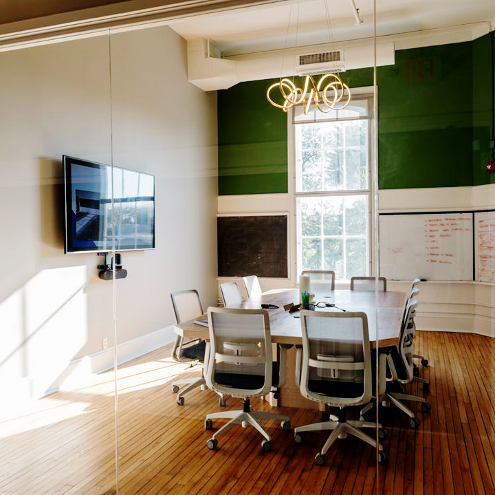 conference room with a large window, a tv, and seven office chairs