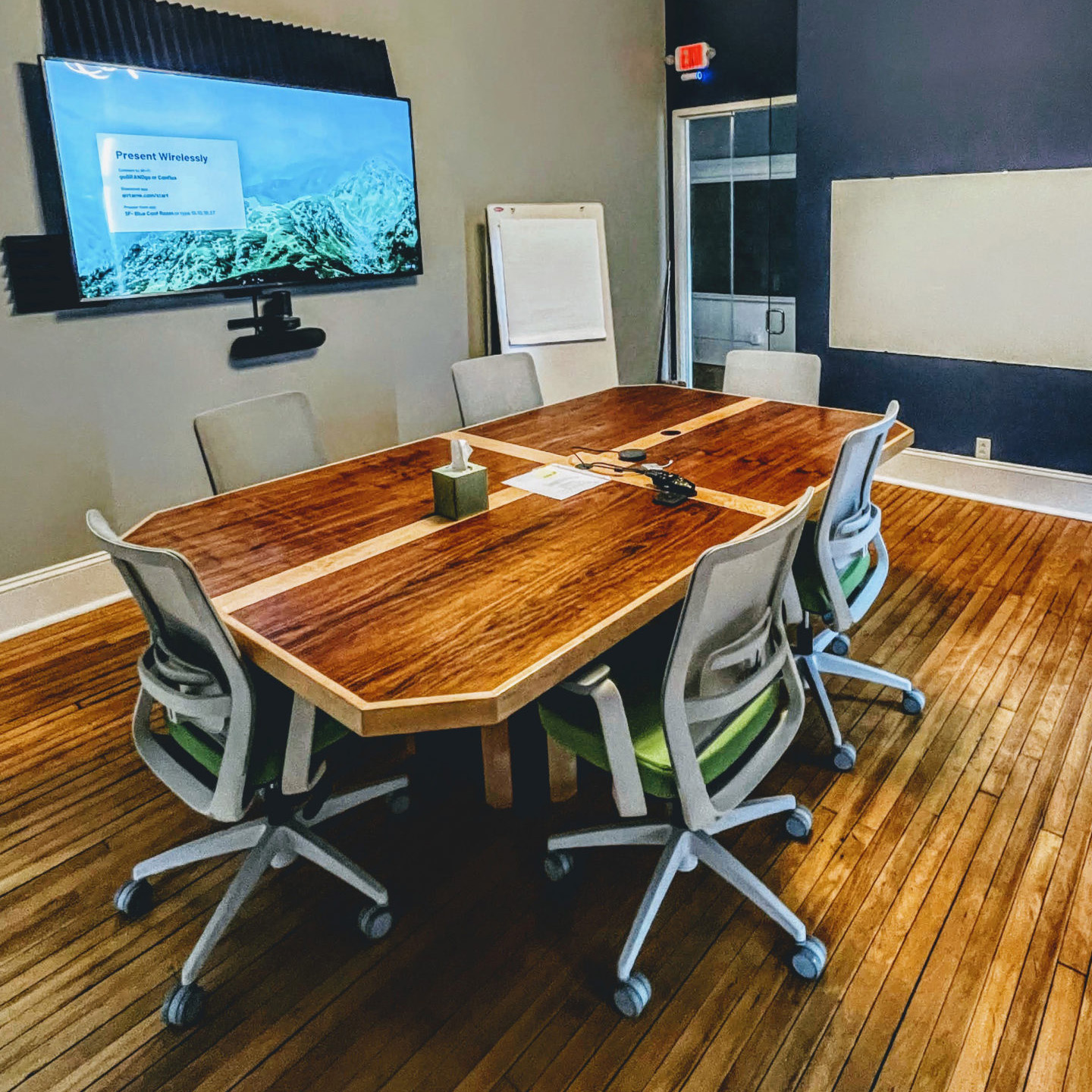 six chairs around a wooden conference table near a tv