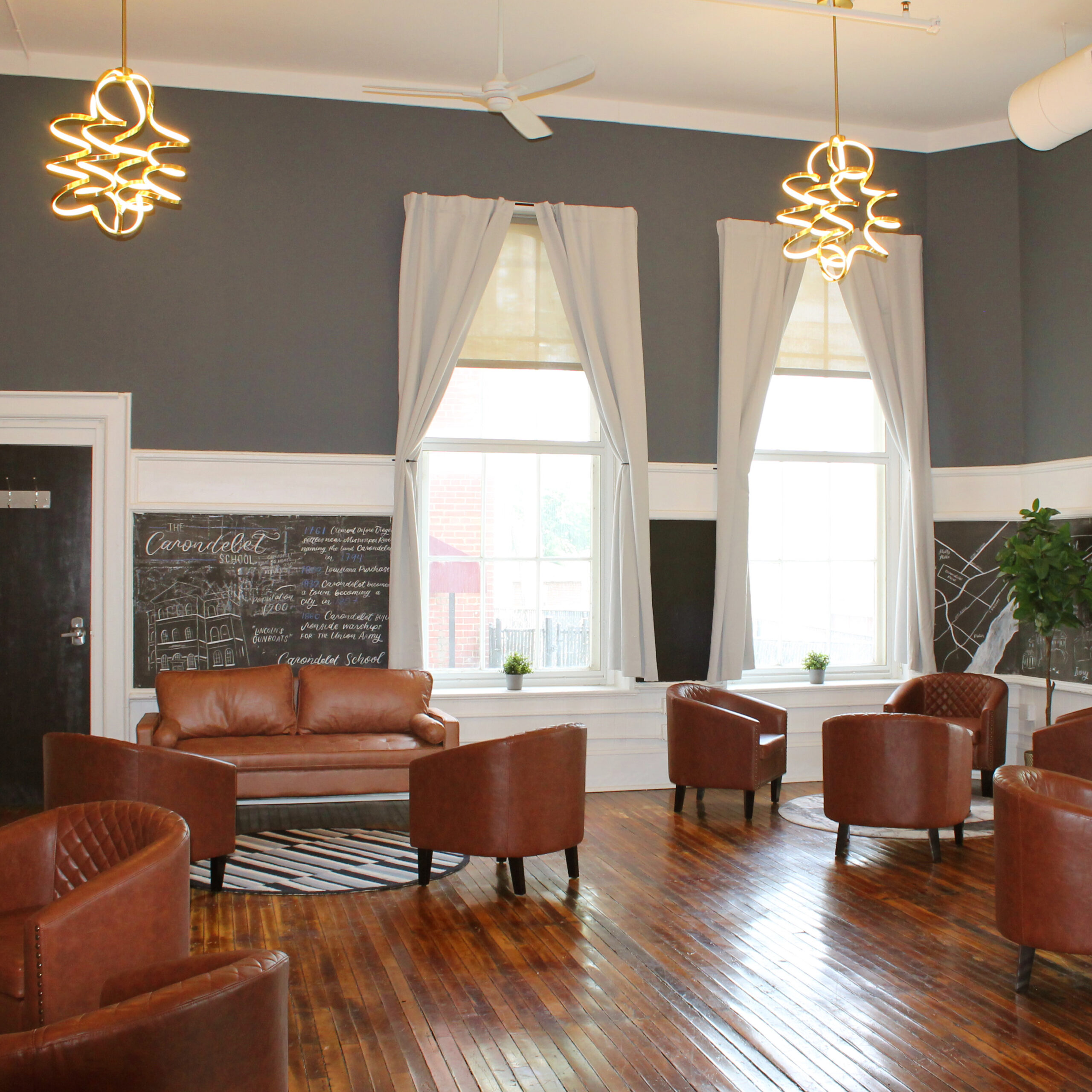 Cozy leather seating illuminated by large windows and modern hanging lights